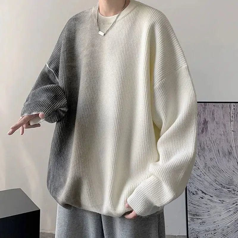 A person wearing a white and grey ombre oversized ribbed sweater and grey pants.
