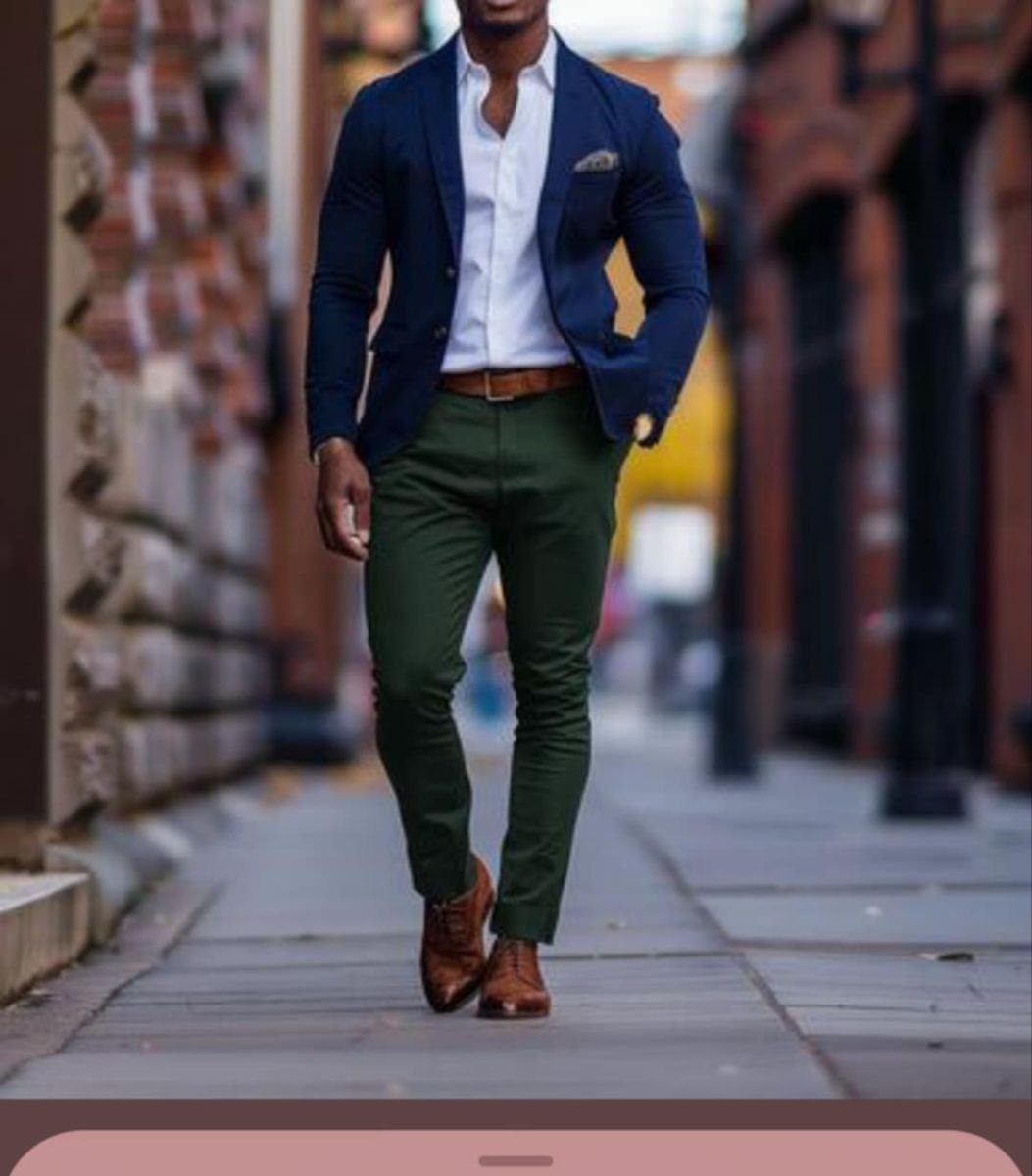 A man walking in a city wearing a navy blazer and green trousers.