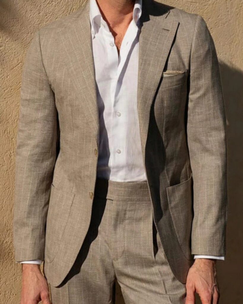 Man wearing a light beige linen suit and a white button-down shirt outdoors.